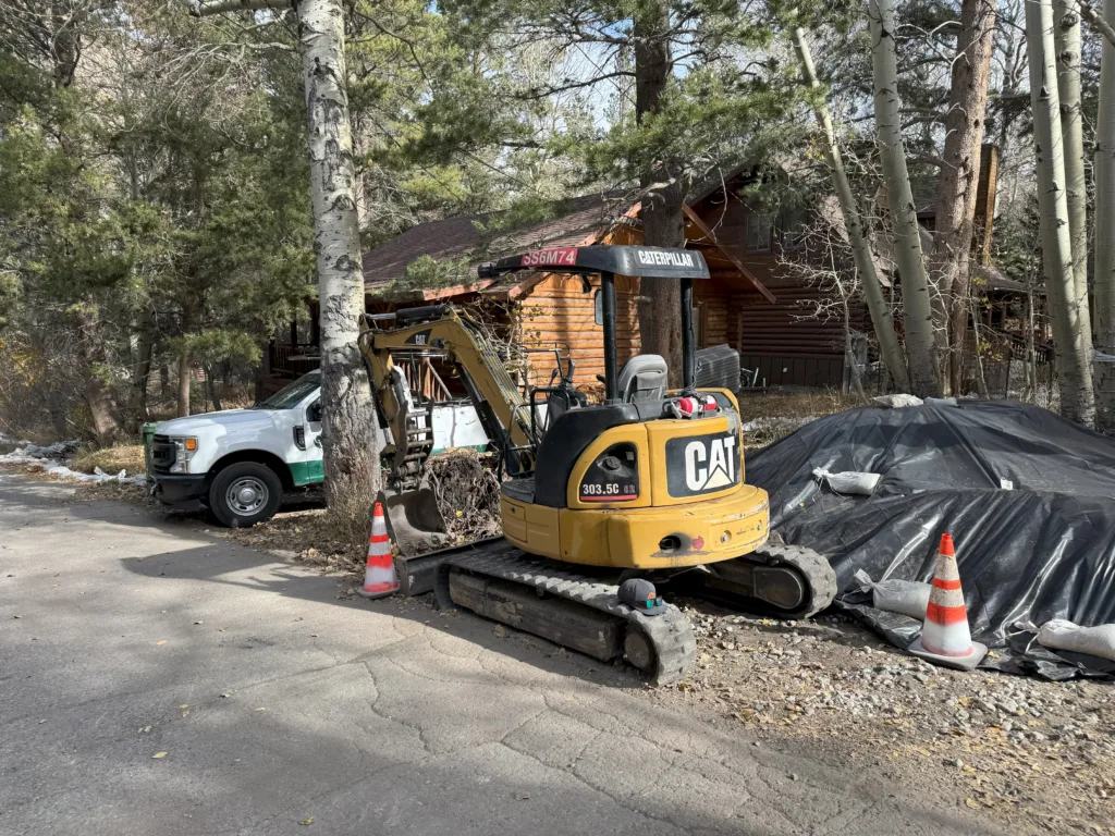 Mini excavator working beside a mountain cabin